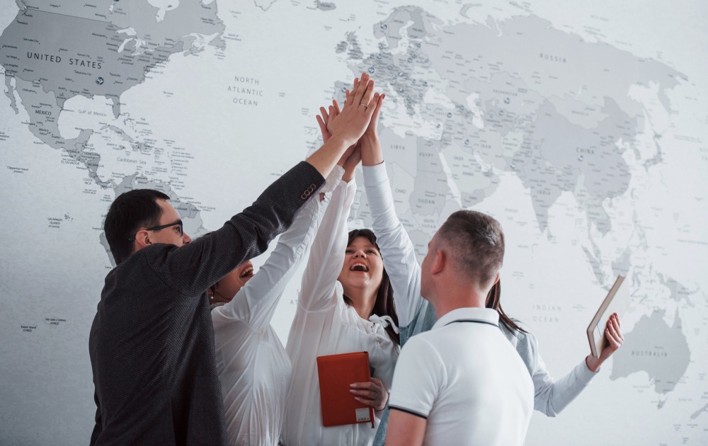 Équipe célébrant la certification ISO 27001 devant une carte du monde - Hucency